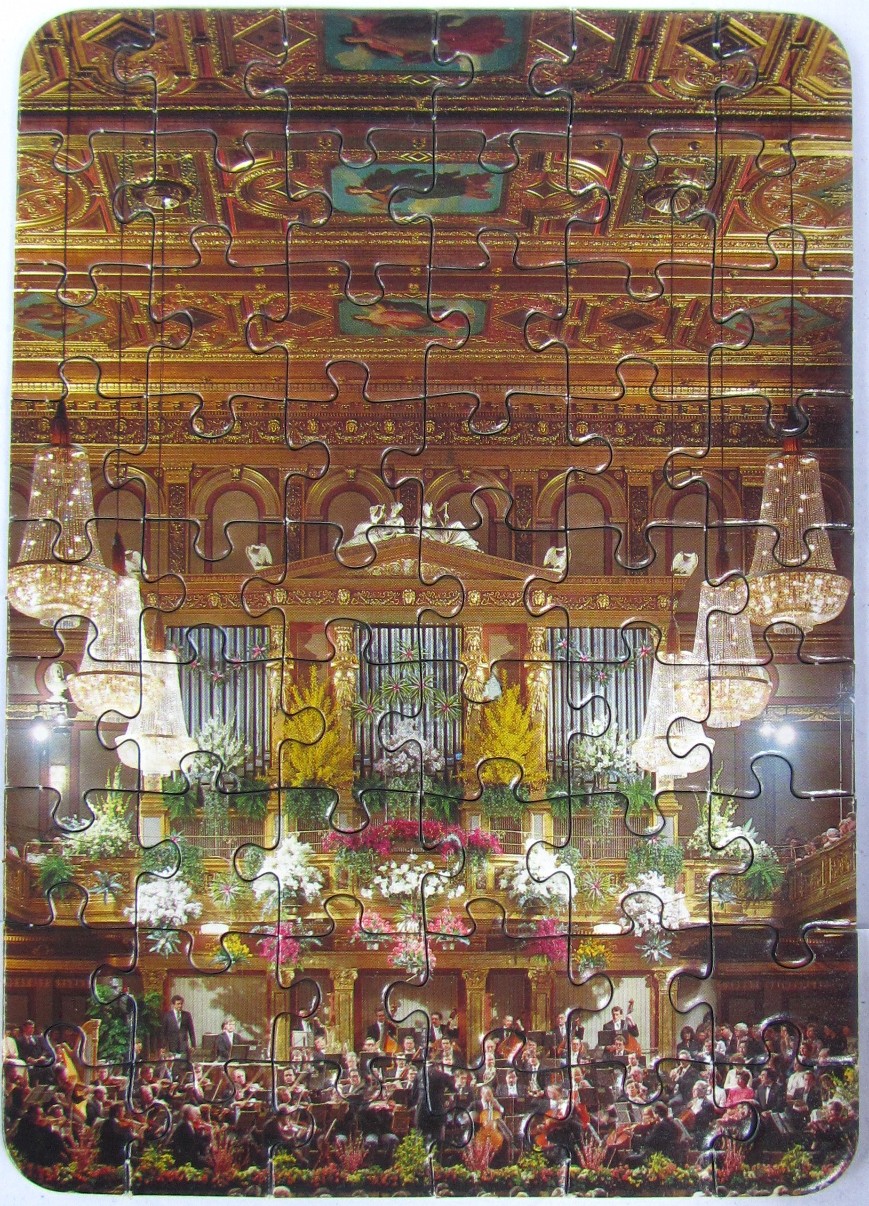 An interior view of a grand concert hall featuring a large pipe organ, elaborate gold ceilings, and a full orchestra.