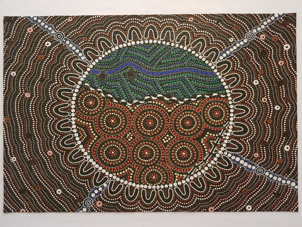 Indigenous Australian style dot painting featuring a central circular motif with green, brown, and blue geometric patterns.