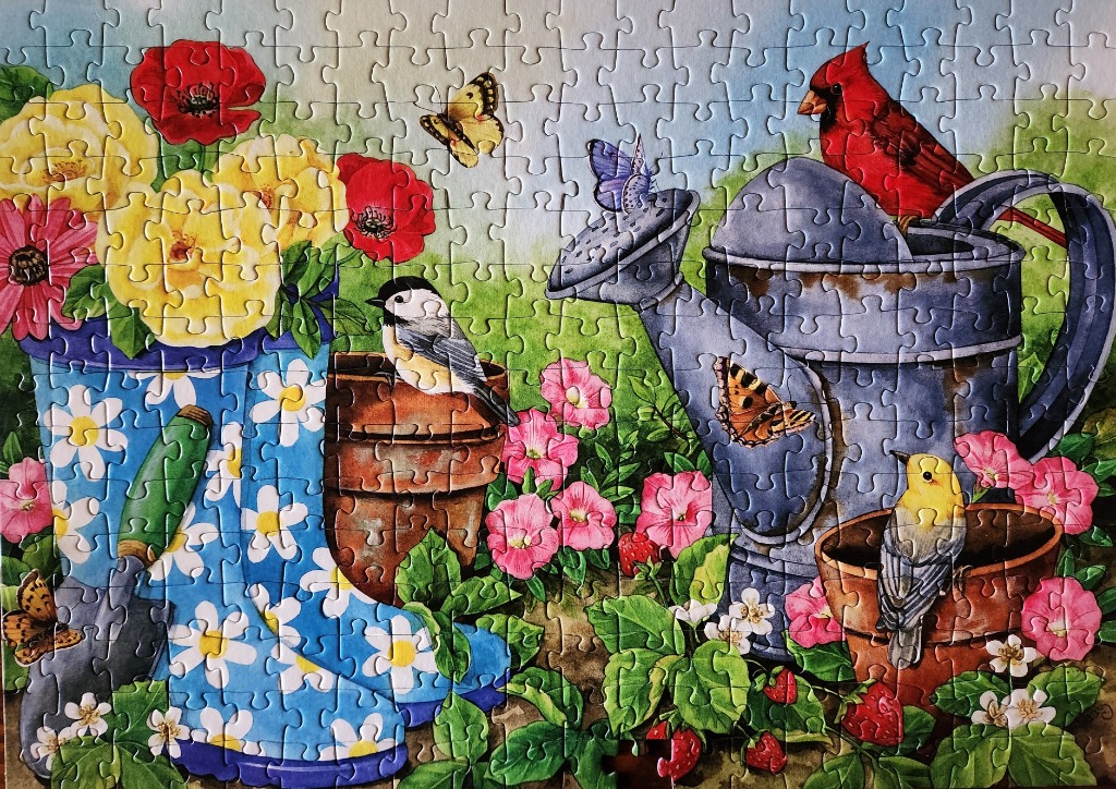 A garden scene featuring a blue daisy-patterned boot filled with flowers, a watering can, birds, and butterflies.