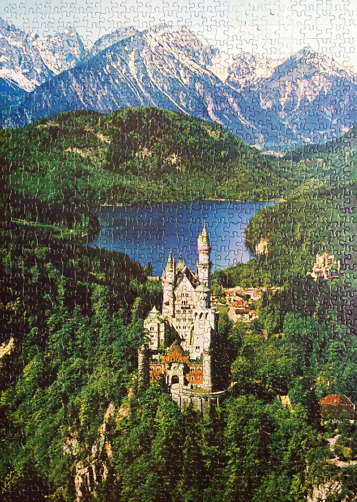 Neuschwanstein Castle nestled in a lush green forest with a mountain backdrop