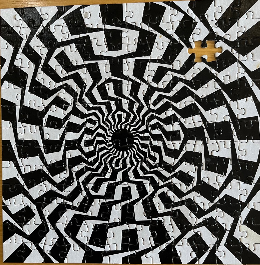 A black and white optical illusion pattern featuring a swirling spiral radiating from a central dark hole.