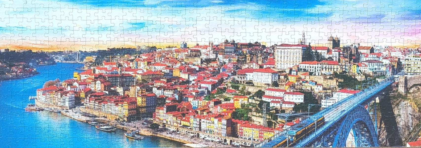 Panoramic view of the city of Porto, Portugal, at sunset, featuring the Douro River and the Dom Luís I Bridge.