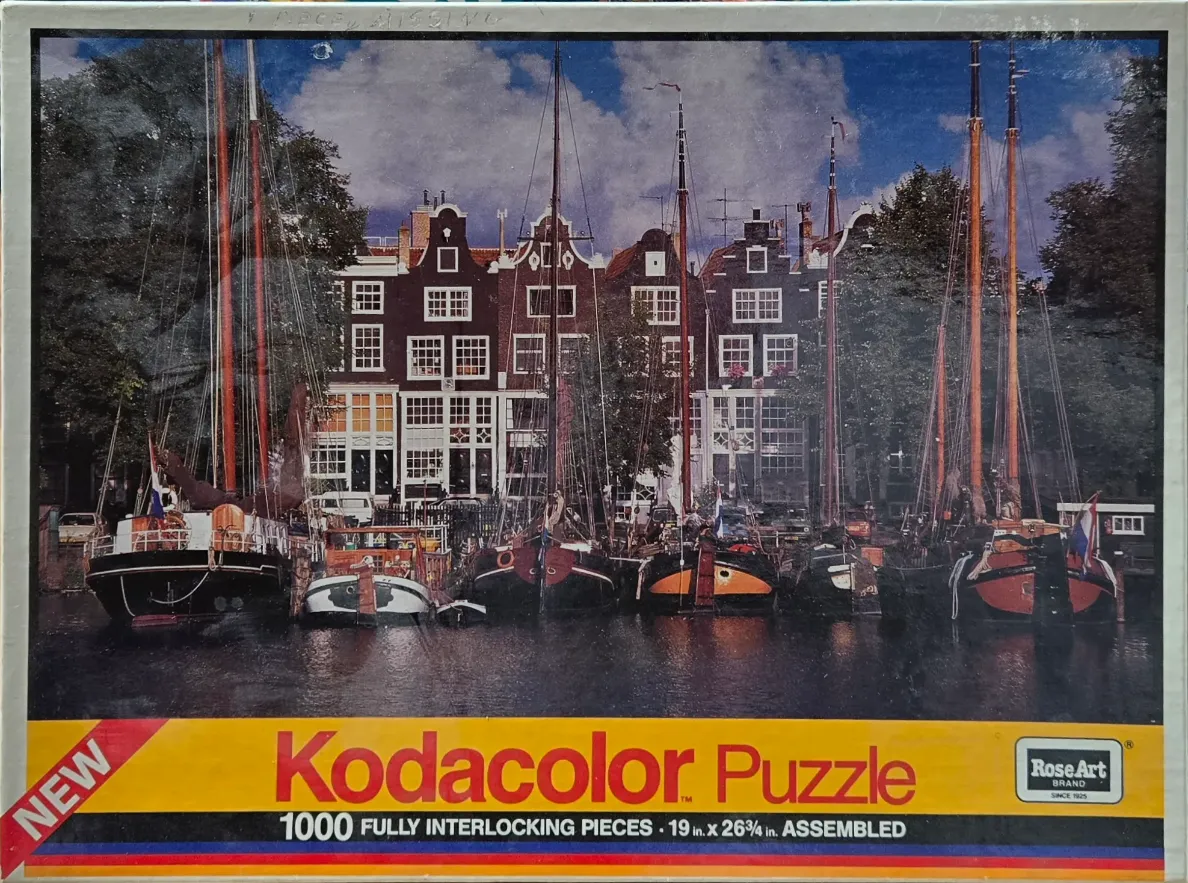 Traditional canal houses in Amsterdam with vintage sailing boats docked in the foreground.