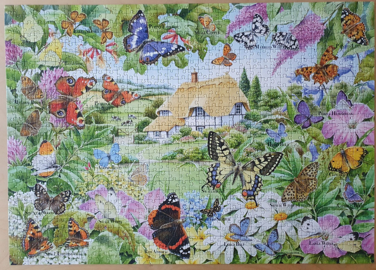 A lush garden scene filled with numerous illustrated butterflies and a thatched-roof cottage in the background.