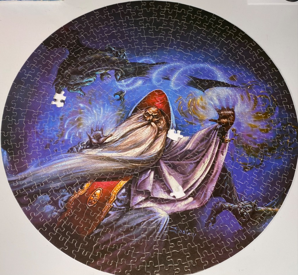 A fantasy illustration of a bearded wizard casting a spell while surrounded by dark dragons in a circular frame.