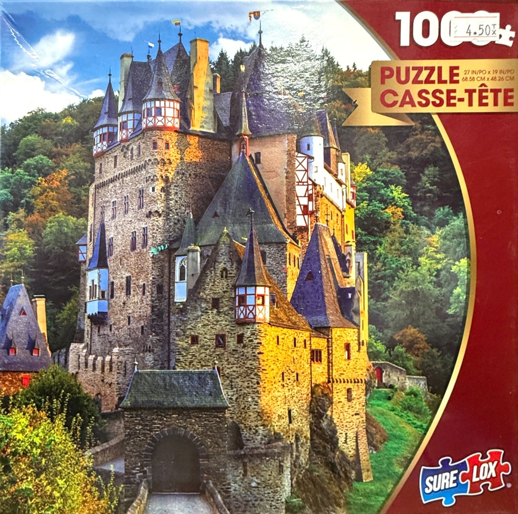 Eltz Castle in Germany nestled in a dense, green forest under a bright blue sky.