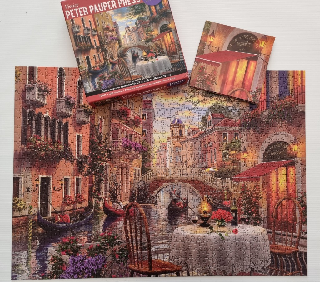 A romantic Venetian canal scene featuring a dining table overlooking the water at sunset.