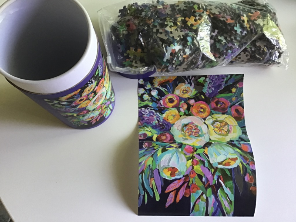 A vibrant, painterly bouquet of flowers on a white surface next to a matching storage canister and a bag of loose parts.