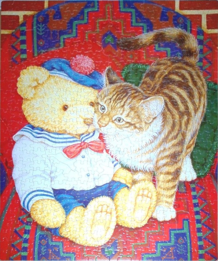 A teddy bear wearing a sailor outfit sits on a rug next to a brown tabby kitten.