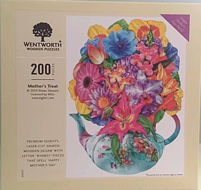 A lush bouquet of vibrant, multi-colored flowers overflowing from a decorative, light blue porcelain teapot.