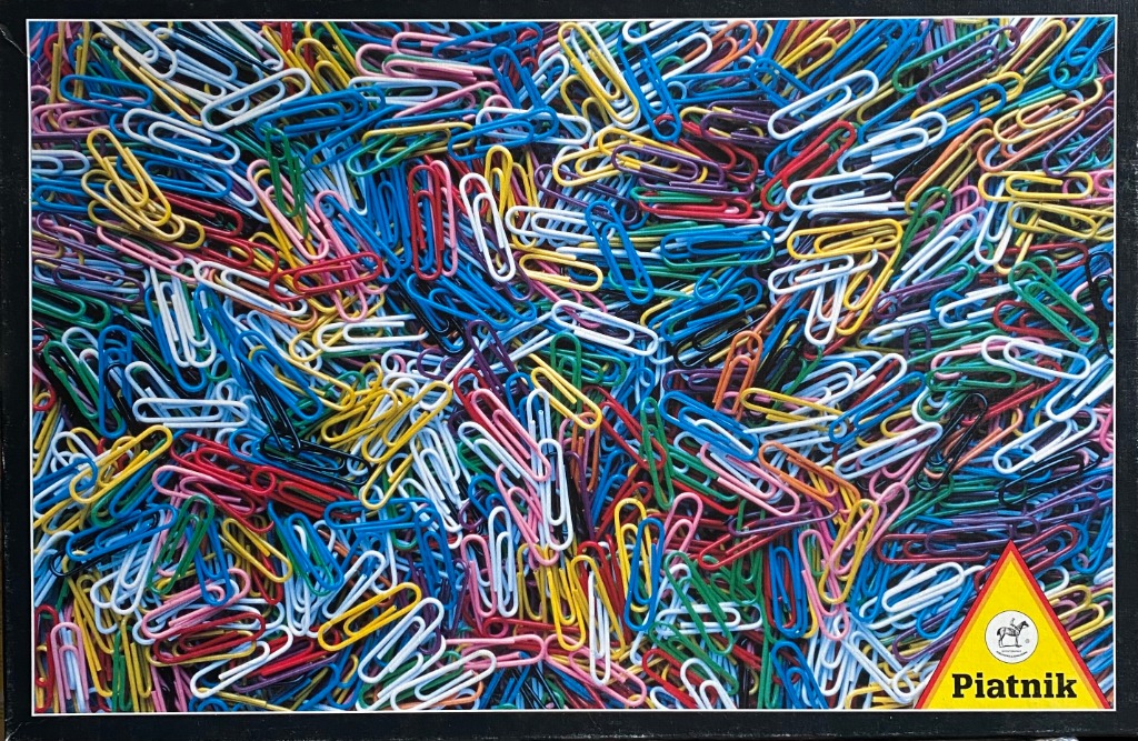 A dense pile of scattered colorful metal paperclips in various shades of blue, yellow, red, green, pink, and white.