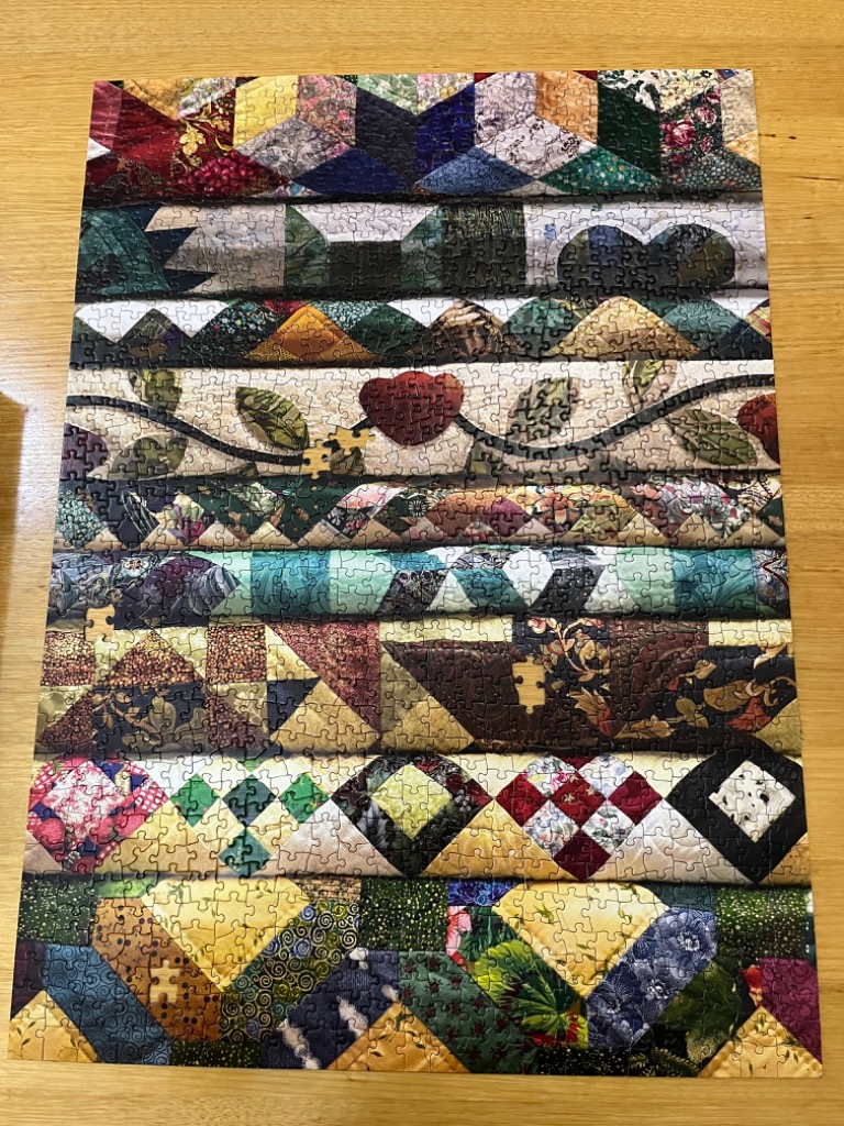 A collection of stacked, colorful fabric quilt blocks with varied geometric patterns and floral motifs.