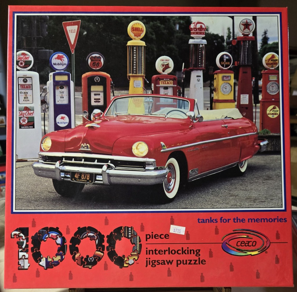 A vintage red convertible parked in front of a row of antique gas pumps.