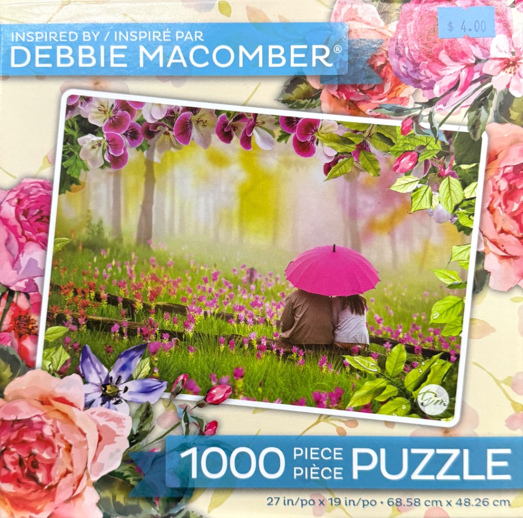 A couple under a bright pink umbrella in a field of wildflowers.