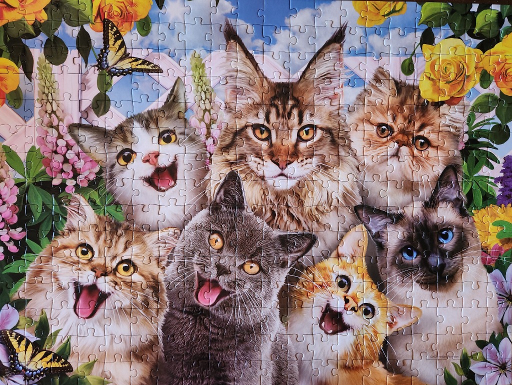 A group of six diverse, expressive cats gathered together in a vibrant garden full of flowers and butterflies.