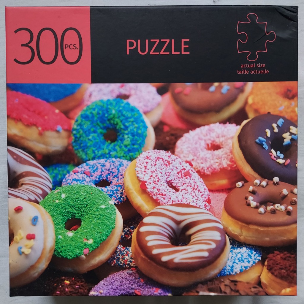 A close-up photograph of a variety of colorful iced and sprinkled donuts stacked together.
