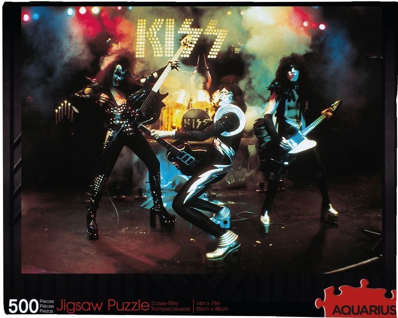 The band KISS performing on a dark, smoky stage with vibrant stage lighting.