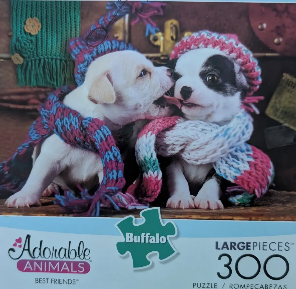 Two small puppies wearing hand-knit scarves and hats, interacting playfully.