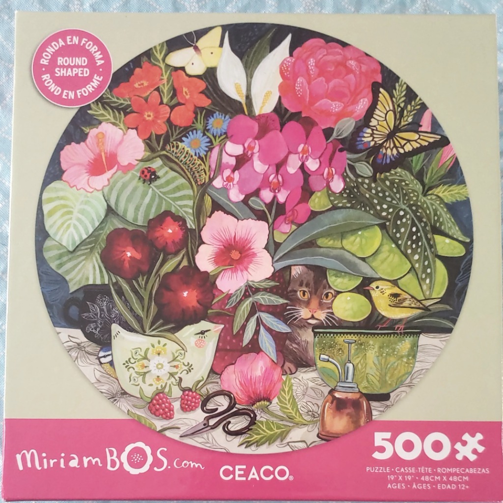 A lush, circular floral arrangement featuring a cat, butterflies, and various vibrant blossoms.