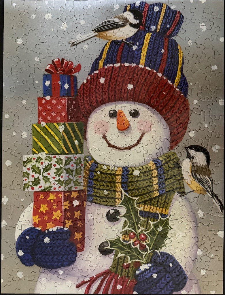 A cheerful snowman wearing a winter hat and scarf, holding a stack of gifts while two chickadees perch nearby.