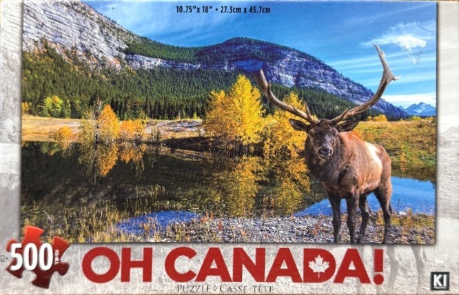 A majestic elk stands by a serene mountain lake reflecting golden autumn trees.