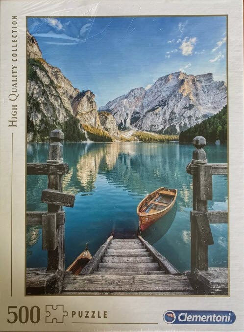 A serene photograph of Braies Lake in Italy, showing wooden docks, rowboats, and towering mountain peaks.