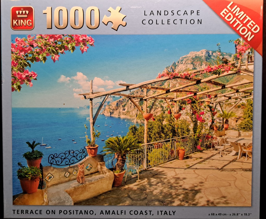 A sunny terrace overlooking the Mediterranean sea in Positano, Italy, with a cat sitting on a stone bench.