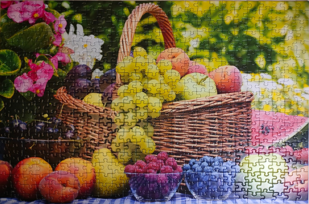 A wicker basket overflowing with fresh fruit, including grapes, peaches, and berries, in a sunlit garden setting.
