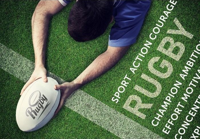 A rugby player reaching forward to place the ball over a white goal line on a green grass field.
