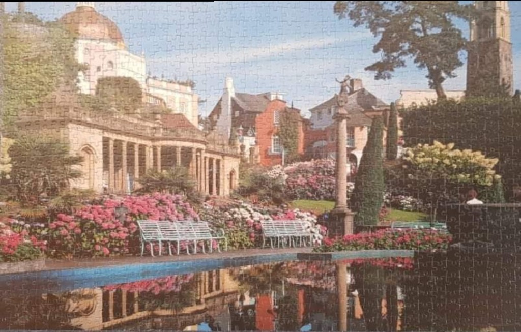 A peaceful garden scene with a reflective pond, classical architecture, and blooming flowers in an Italianate style.