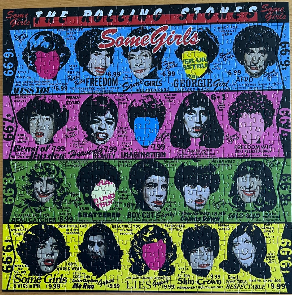 An album cover art collage featuring twenty stylized portraits of band members styled as women with various wigs.