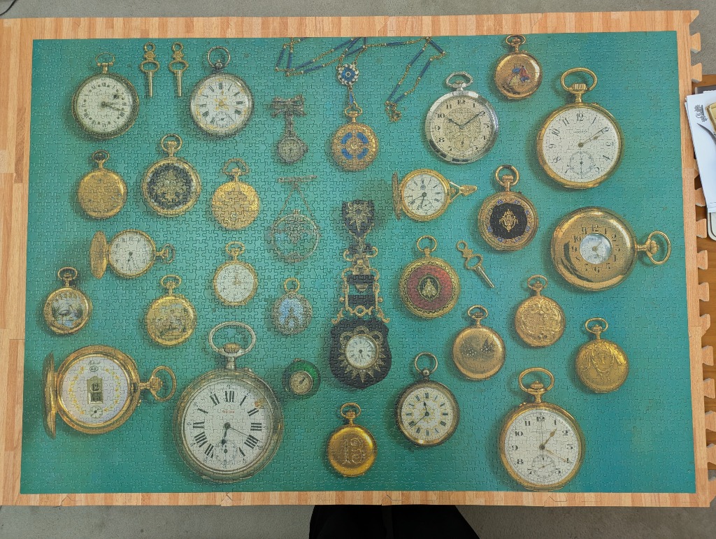 Collection of various vintage antique pocket watches arranged on a teal background