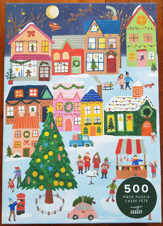 Whimsical Christmas village illustration with a large central tree, colorful houses, and snow-covered streets.