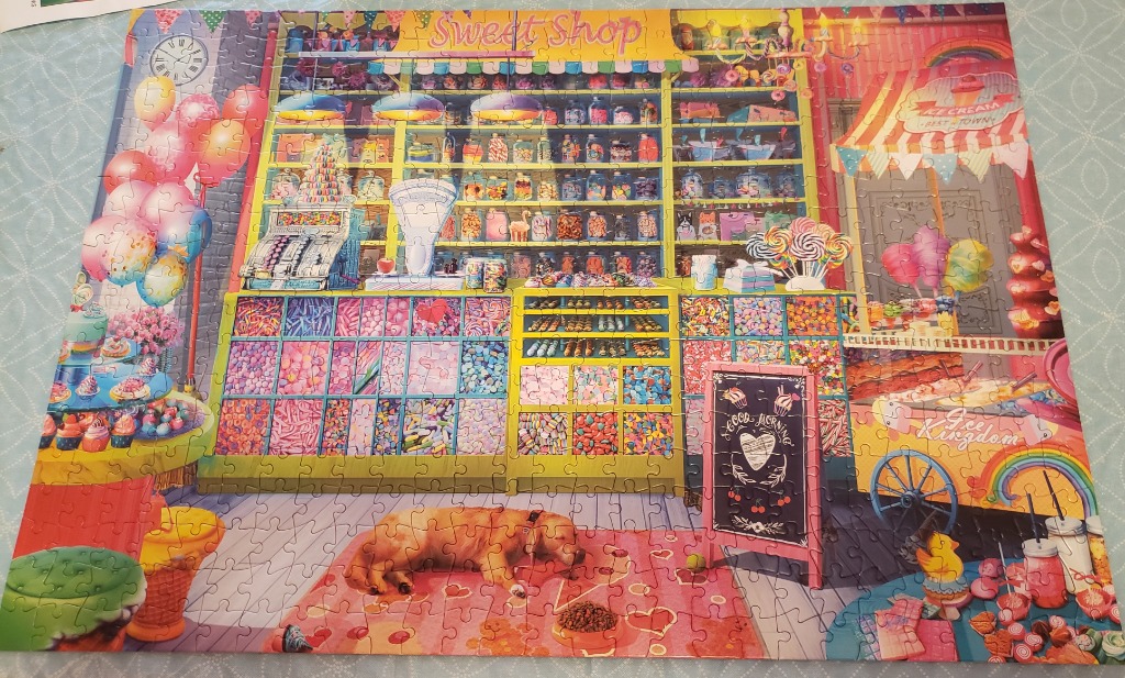 A colorful, whimsical illustration of a candy shop interior featuring a sleeping dog on a heart-patterned rug.