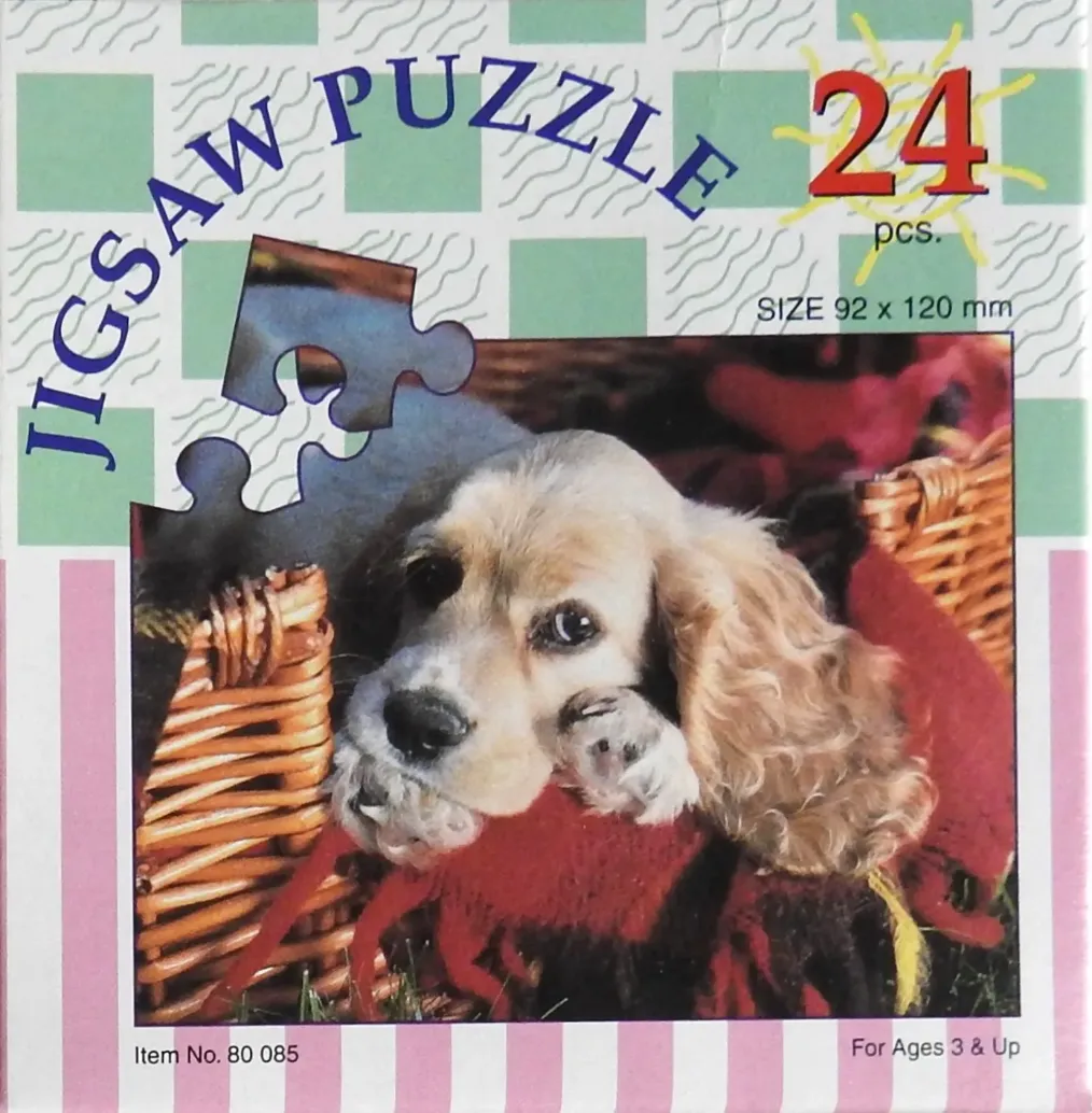 A close-up photograph of a golden spaniel puppy resting its chin on a red cloth inside a wicker basket.