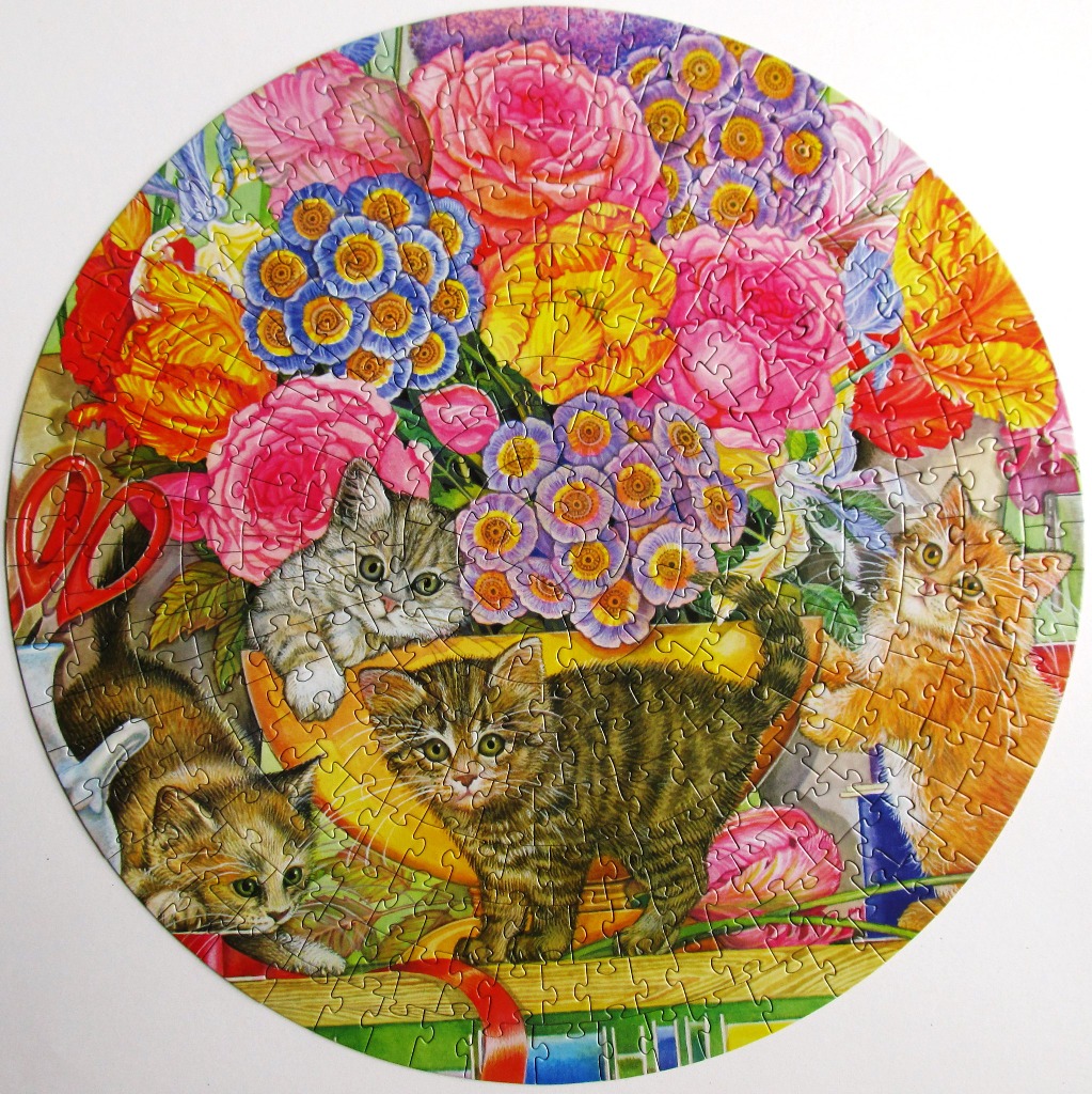 Three kittens playing amidst a vibrant, circular floral arrangement.