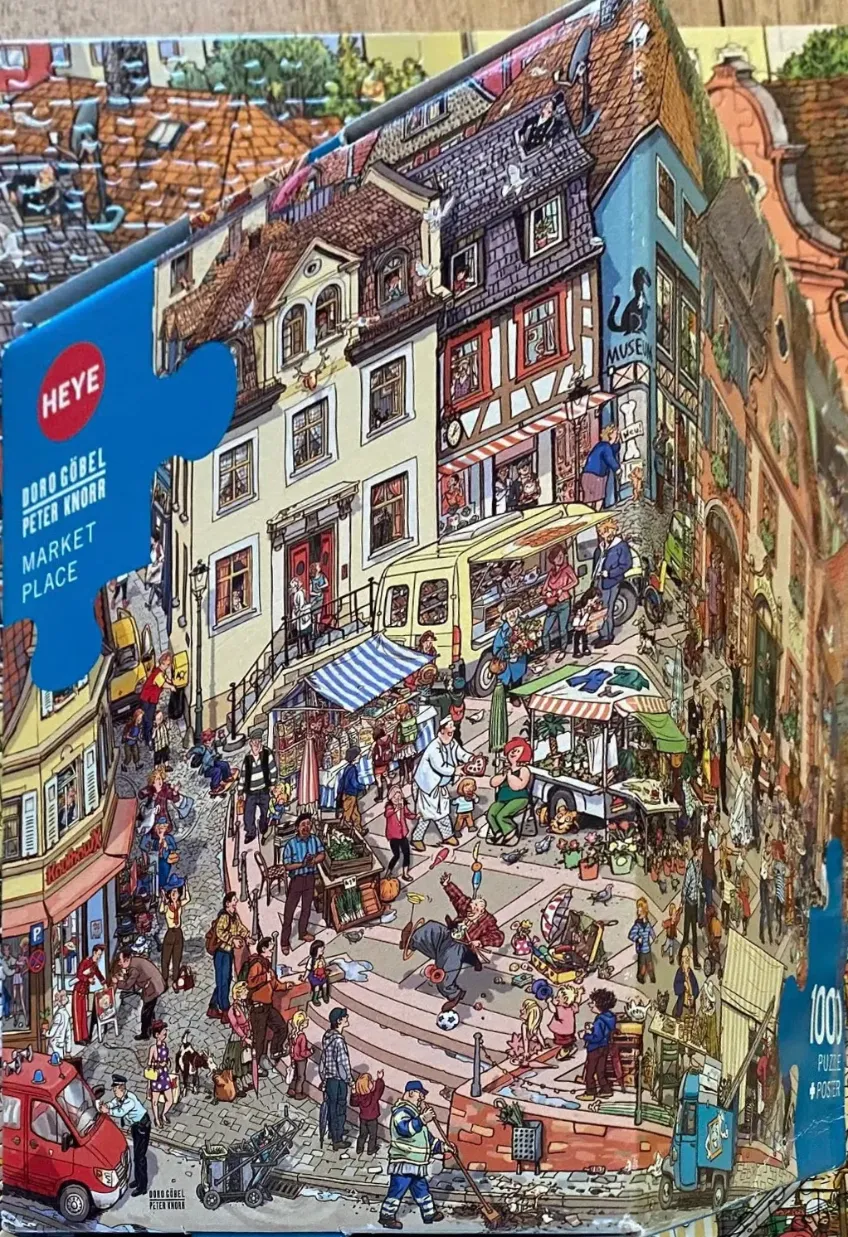 A busy European town market square illustration filled with many small figures, vendors, and detailed architecture.
