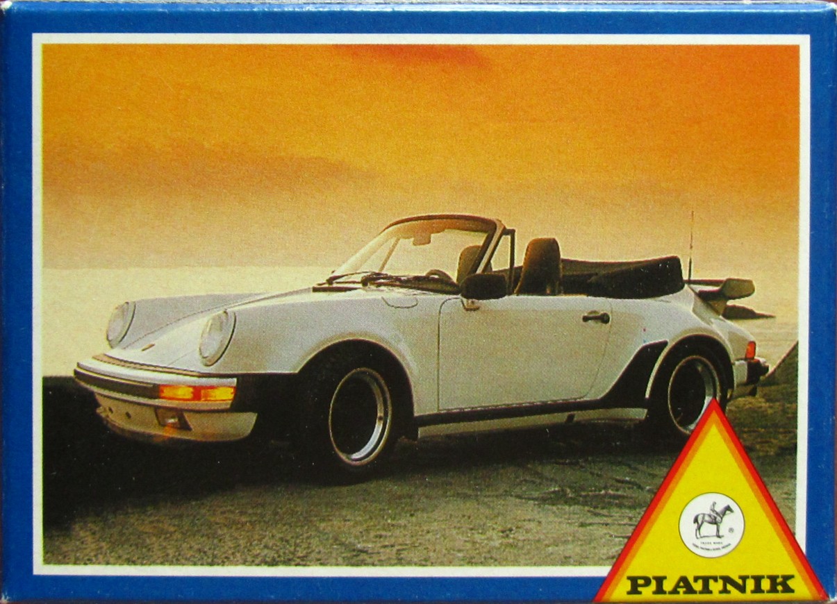 A white vintage convertible sports car parked against a sunset sky.