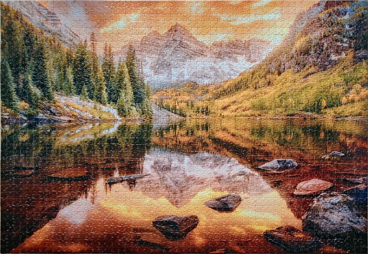 The Maroon Bells mountain peaks reflected in a calm lake during autumn sunset.