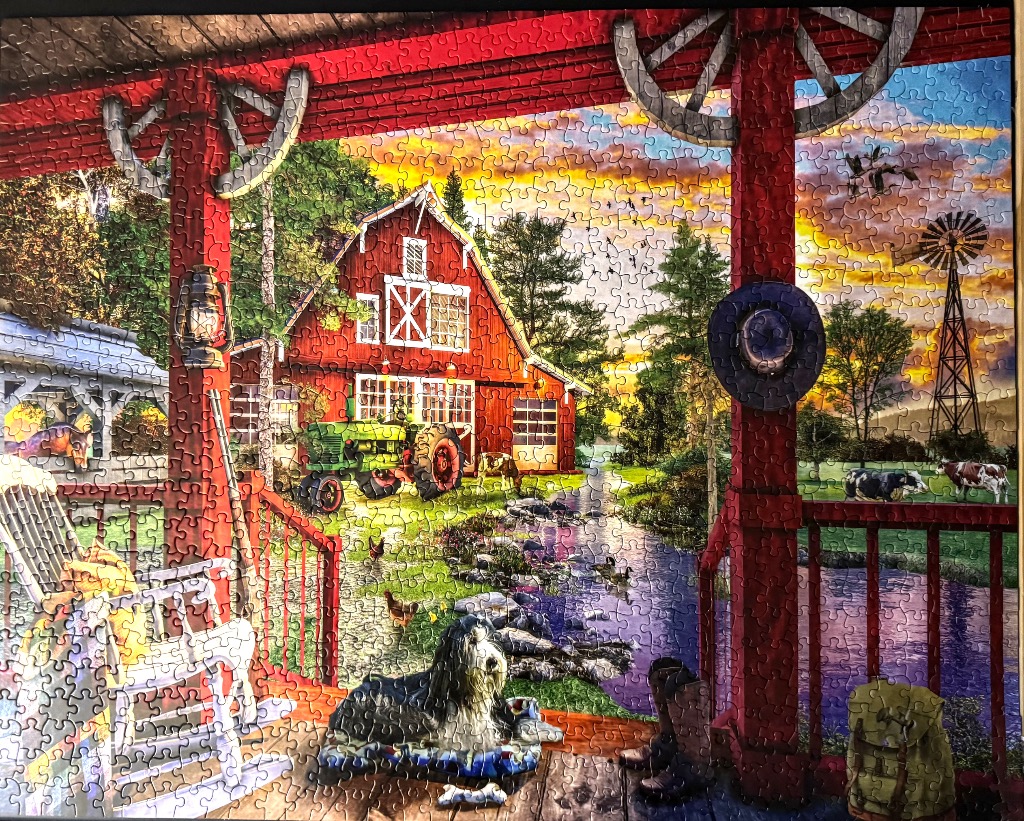 A peaceful farm scene viewed from a red porch featuring a barn, a green tractor, and a shaggy dog.
