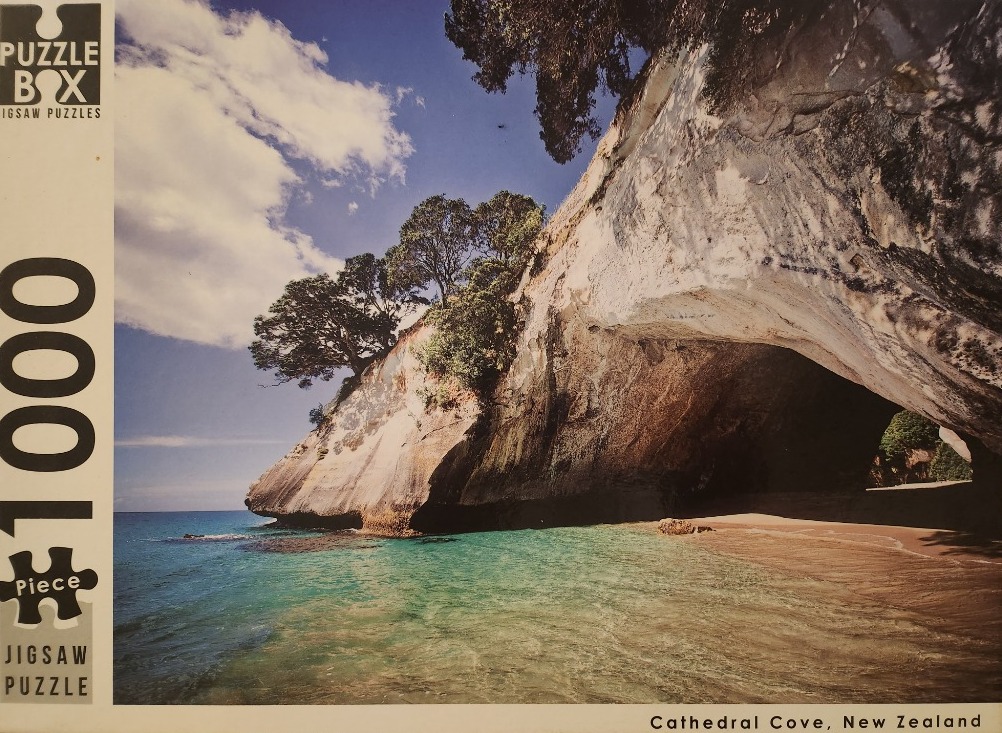A sunny photograph of the arched rock formation at Cathedral Cove in New Zealand.
