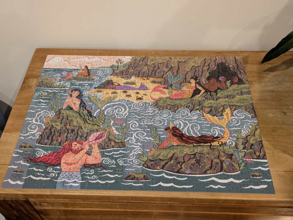 An illustration of various merfolk interacting with a rocky tropical coastline.