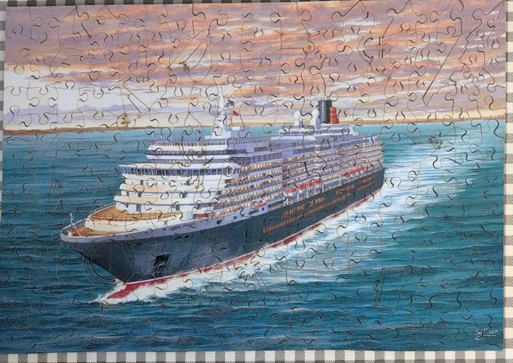 A luxury ocean liner sailing through deep blue water under a sunset sky.
