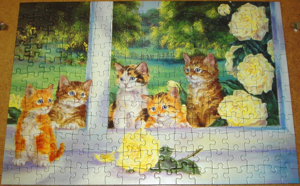 A painting of four kittens sitting in a window with yellow roses.