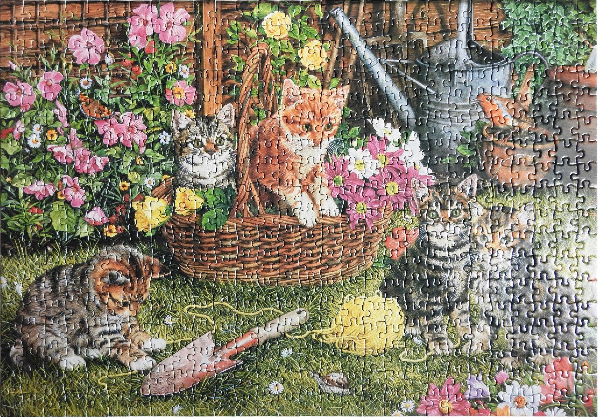 Four kittens in a garden with flowers and gardening tools