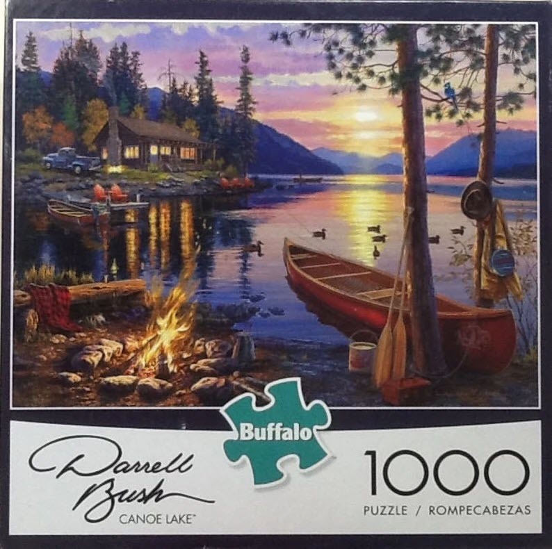 A peaceful lakeshore scene at sunset with a log cabin, a red canoe, and a campfire.