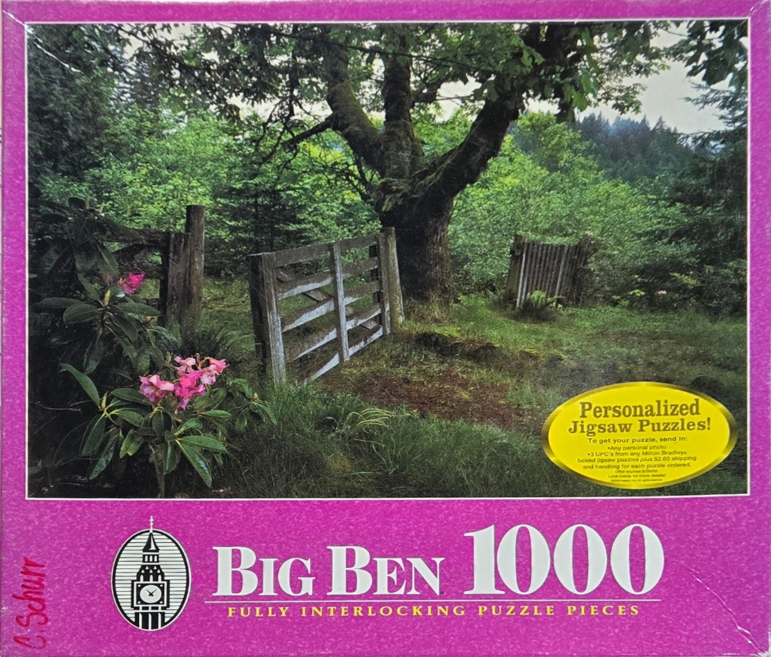A photograph of a rustic wooden gate in a lush, green woodland setting with bright pink rhododendron flowers.