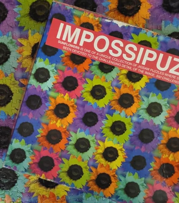 A repeating pattern of colorful sunflowers on a vibrant blue and purple background.