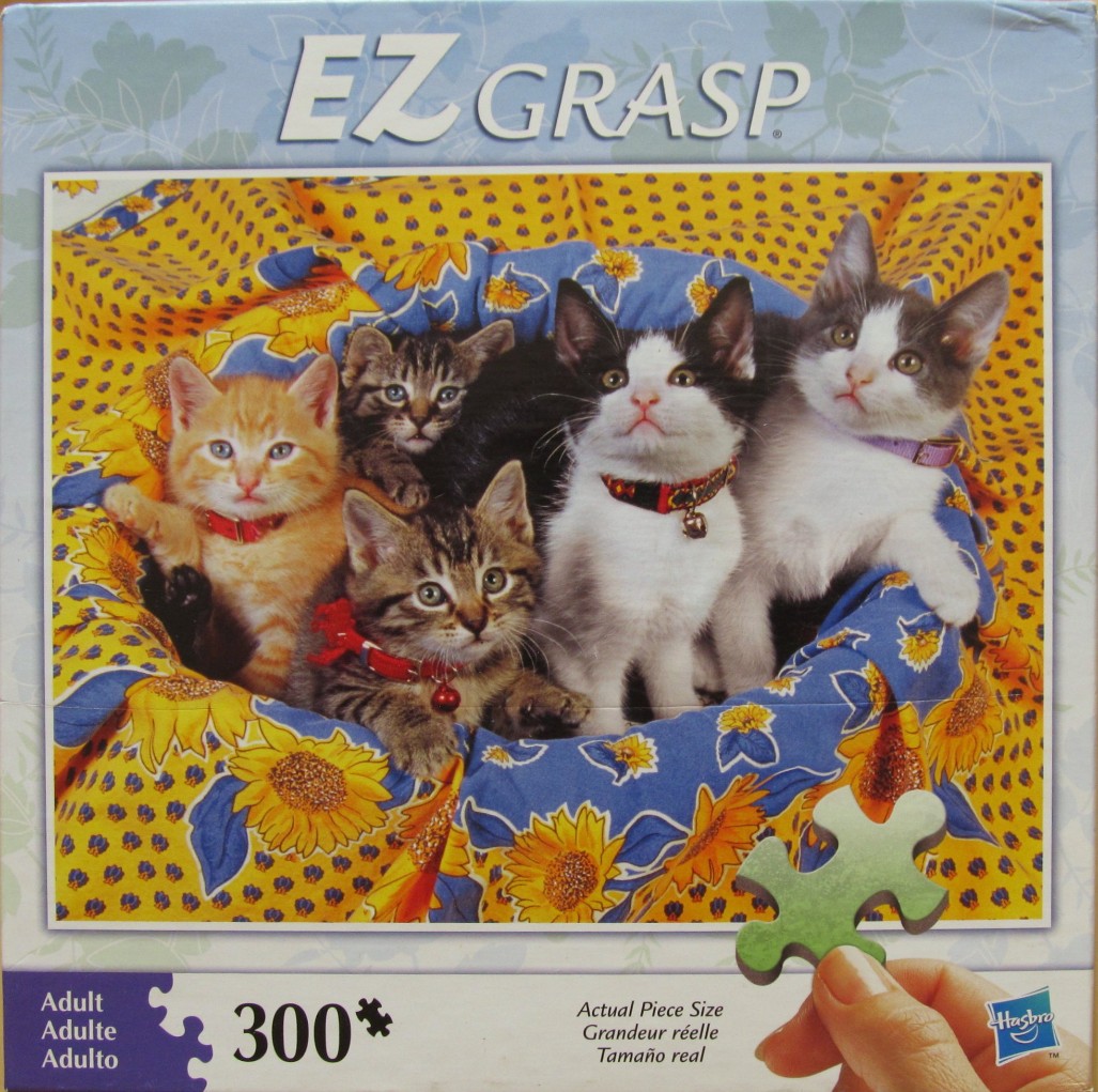 Four kittens wearing collars sitting together in a sunflower-patterned basket