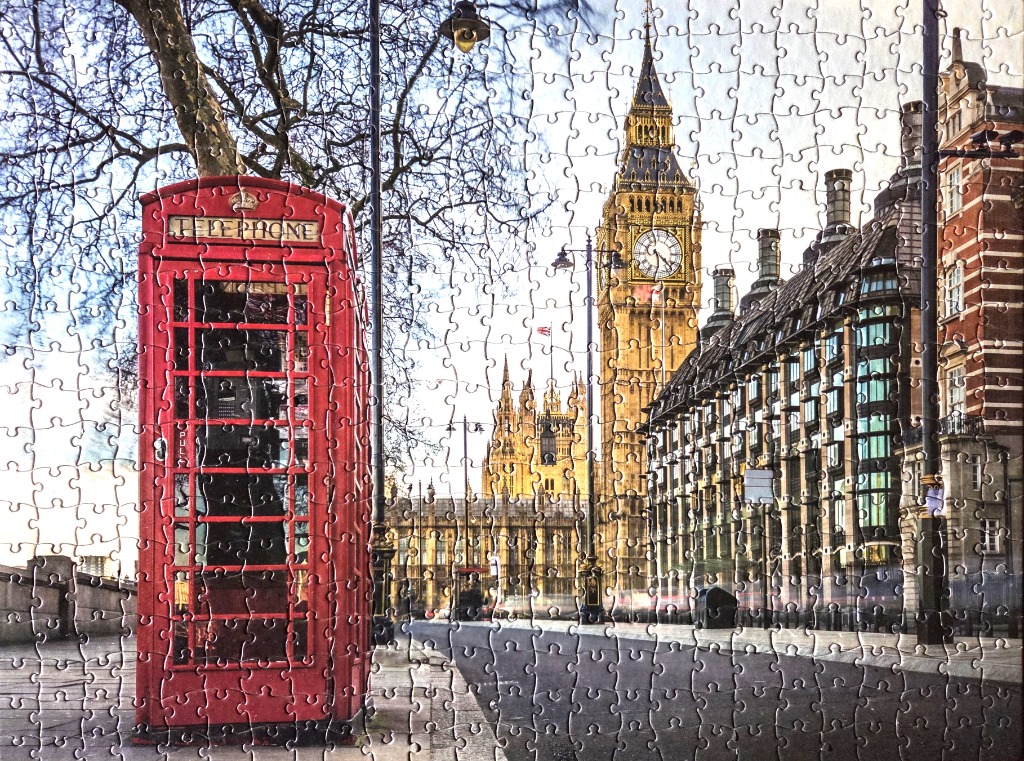 A classic red London telephone booth in the foreground with Big Ben and the Houses of Parliament in the background.